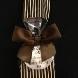 6 Pc Cashew Bruttle Bag.  Cashew Bruttles wrapped in silver foil and put into a cream colored cello bag with brown polka dots and closed with a brown satin bow.
