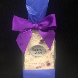 Huckleberry Bark in a clear cello bag with gold polka dots and closed with a purple satin ribbon