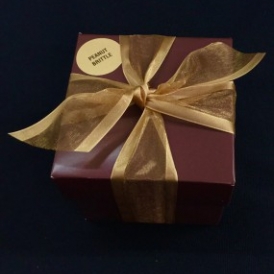 8 ounces Old Fashioned Peanut Brittle in a gold and white stripped box with gold ribbon